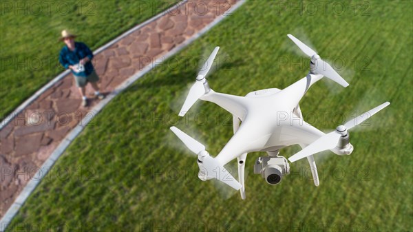 Drone quadcopter (UAV) in air above pilot with remote controller