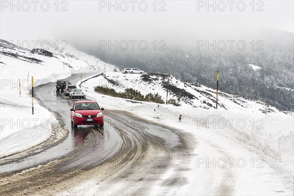 Car driving on winding road through foggy snowy landscape