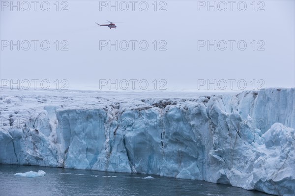 Helicopter flying over a very huge glacier on Mc Clintok or Klintok Island