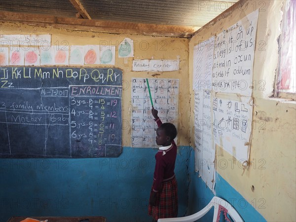 School child in a village school spelling English letters