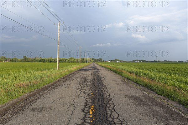 Country road across fields with storm clouds