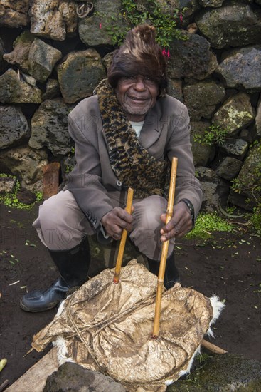 Man using animal skin to start a fire at a ceremony of former poachers