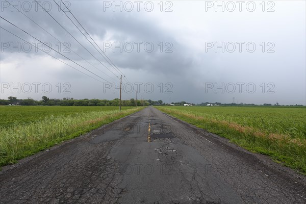 Country road across fields with storm clouds