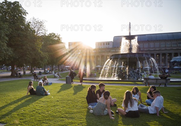 Young people enjoying summer evening on Schlossplatz in front of Koenigsbau