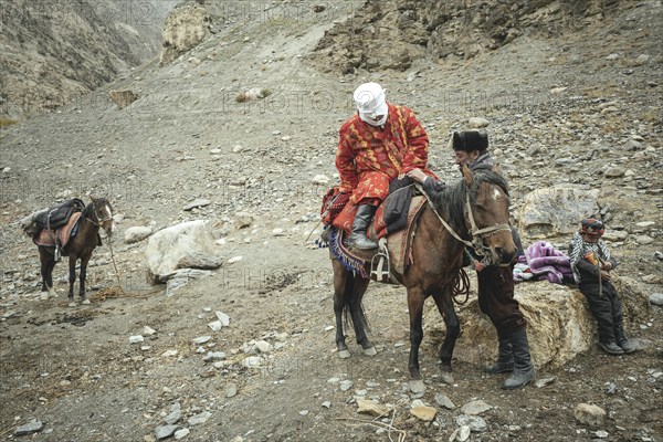 A man helps his pregnant woman onto a horse