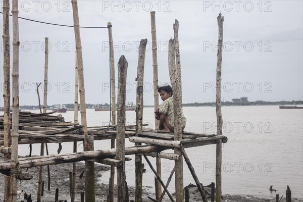 A boy sits on a jetty