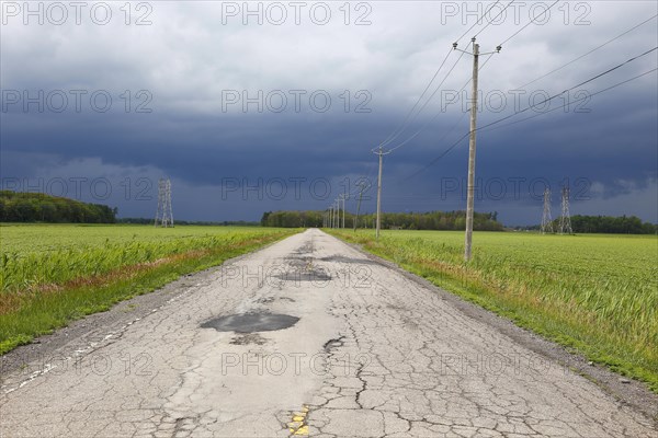 Country road across fields with storm clouds
