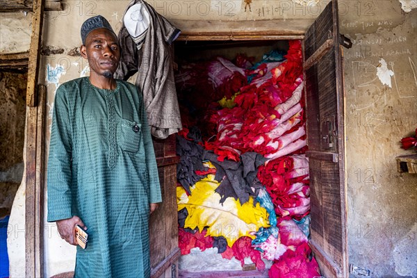 Shopkeeper before his shop full of colourful leather