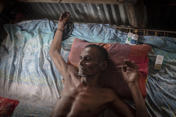 Man on his bed in his hut