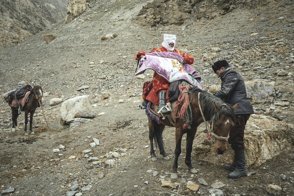 A man helps his pregnant woman onto a horse