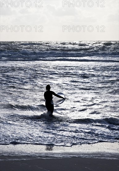 Surf rider goes with her surfboard into the North Sea