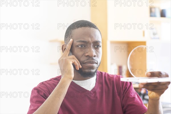 Young black man with sample reconsiders a vision or innovation in the office