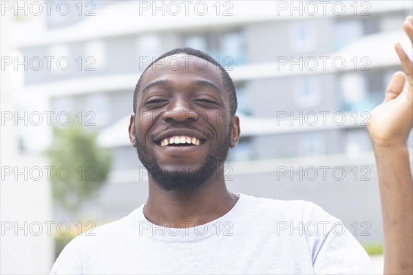 Young black man laughing outside in the summer of the city