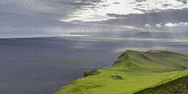 Old farmstead at Hjoerleifshoefdi (Viking grave) behind wide lava sand area and the Reynisdrangar