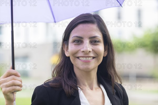 Middle aged serious manager outside with umbrella in hand