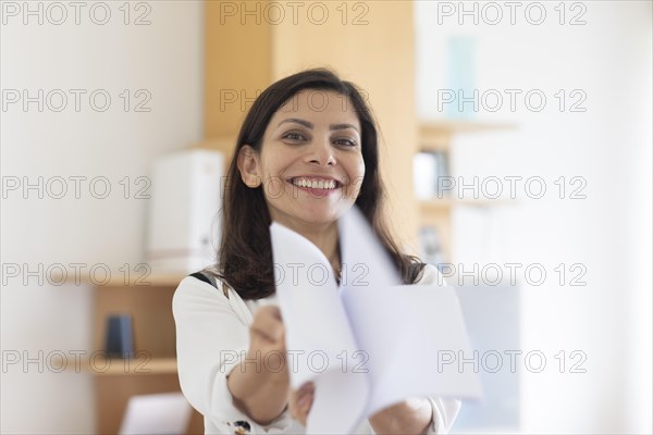 Middle aged serious manager with paper in hand in office