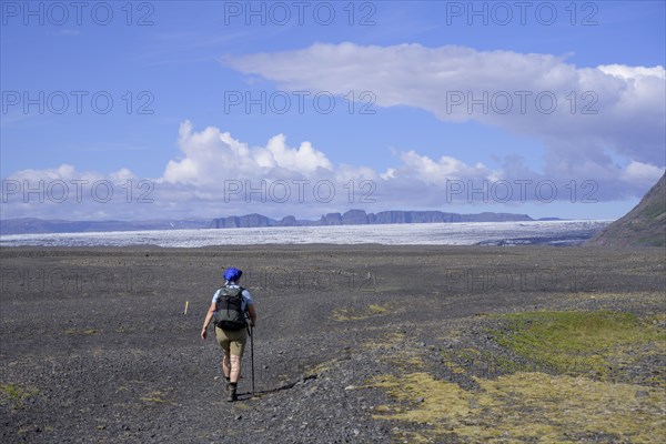 Woman hiking on a wide gravel surface in Morsardalur