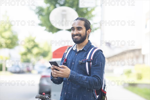 Young man with TSmart phone checks rental bike in the city