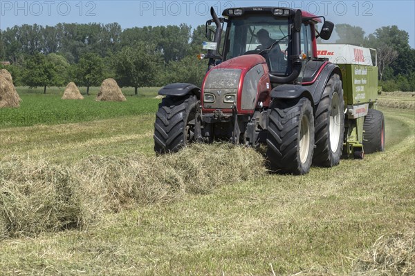 Tractor at the hay baler on the field