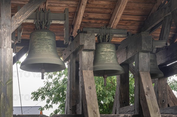 A belfry standing on the ground with four bells of different sizes in the village of Miloradz