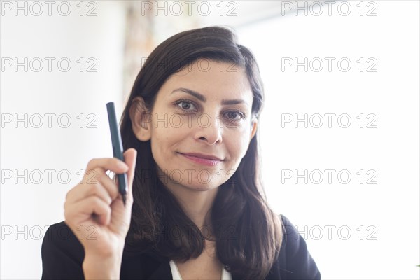 Middle aged serious manager with pen in hand in office