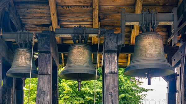 A belfry standing on the ground with four bells of different sizes in the village of Miloradz