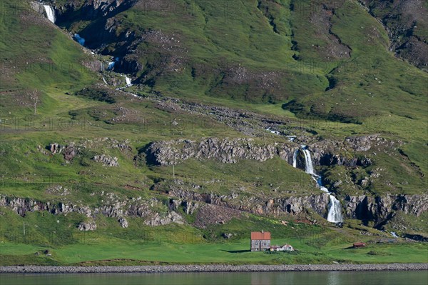 Remote farm in front of a waterfall