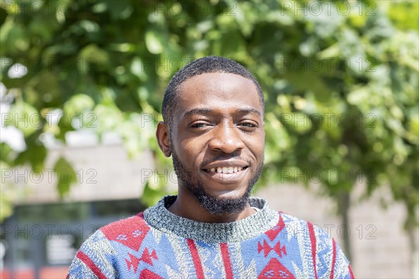 Young black man sitting on bench with African poncho