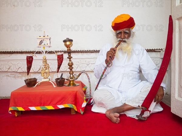 Elderly Indian man with turban smoke hookah