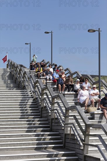 Holidaymakers sitting on wooden steps one behind the other