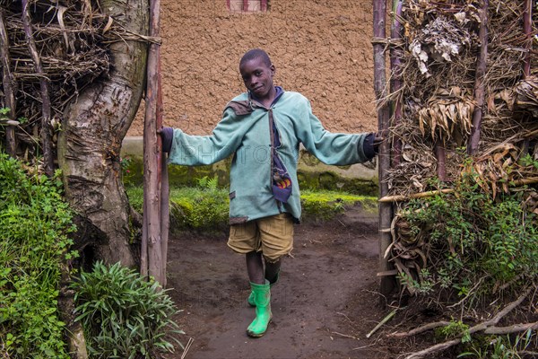 Young boy standing at the doorsteps of mud hut