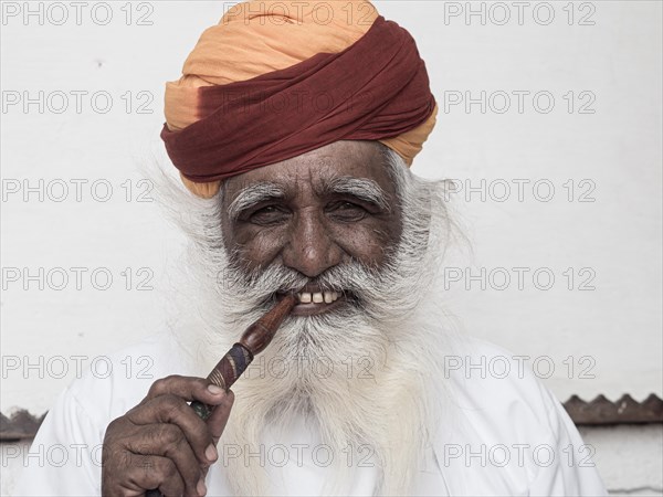 Elderly Indian man with turban smoke hookah