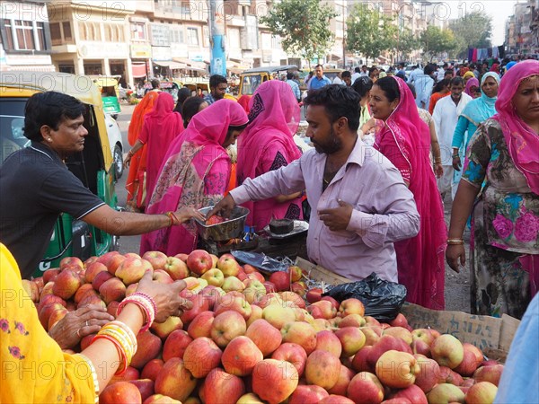 Vendor offering fresh apples at the market stall