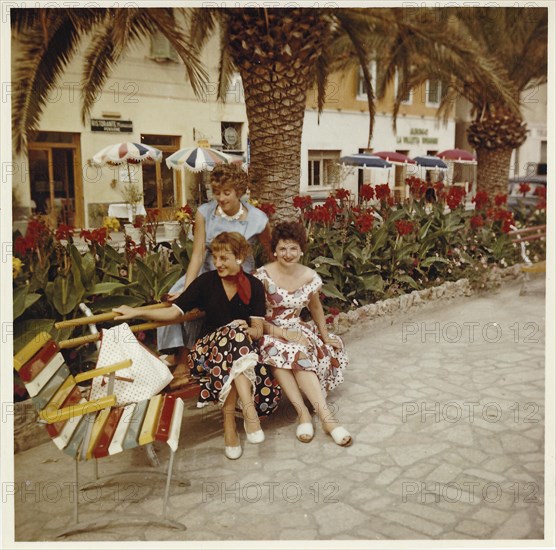 Three young German holidaymakers sitting on the beach promenade of Finale Ligure