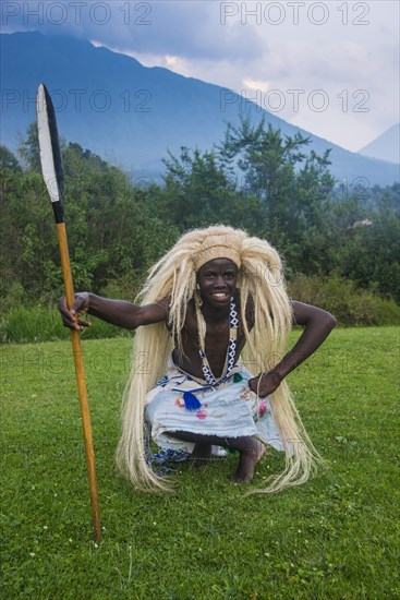 Man wears a wig carries a spear at a ceremony of former poachers