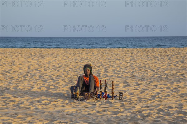 Souvenir seller sitting in the sand on the beach of Santa Maria