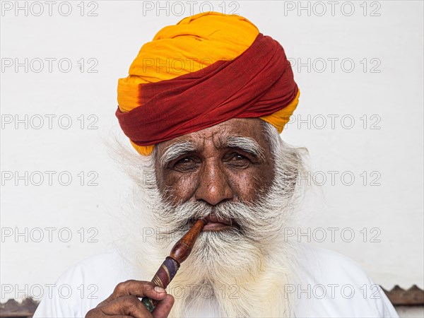 Elderly Indian man with turban smoke hookah