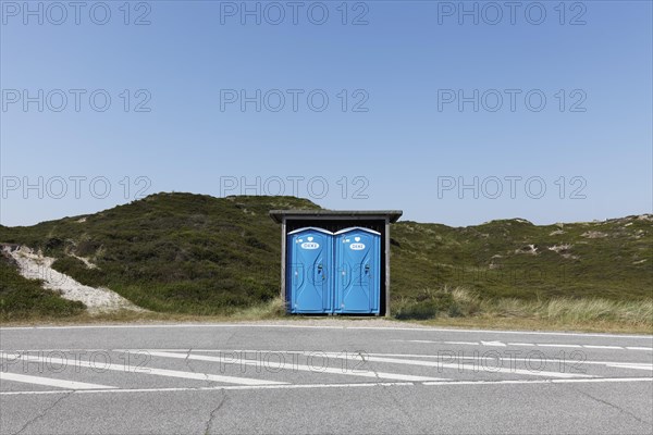 Two blue DIXI toilet stalls on a road