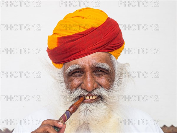 Elderly Indian man with turban smoke hookah