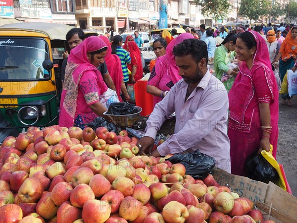 Vendor offering fresh apples at the market stall