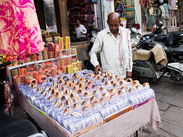 Vendor offering jewellery at market stall