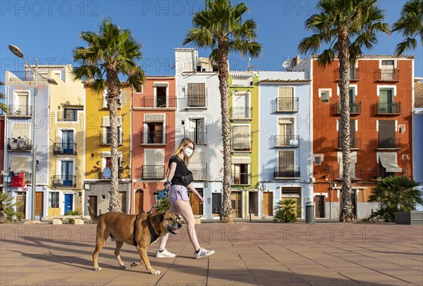 Young woman walks dog in front of Colorful beachfront houses