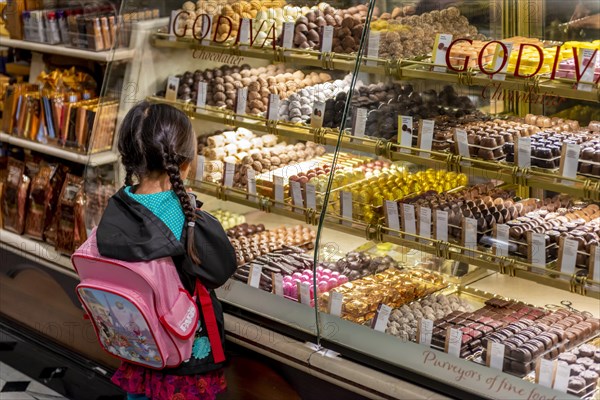 Little girl with pigtails looking at a display of various chocolates