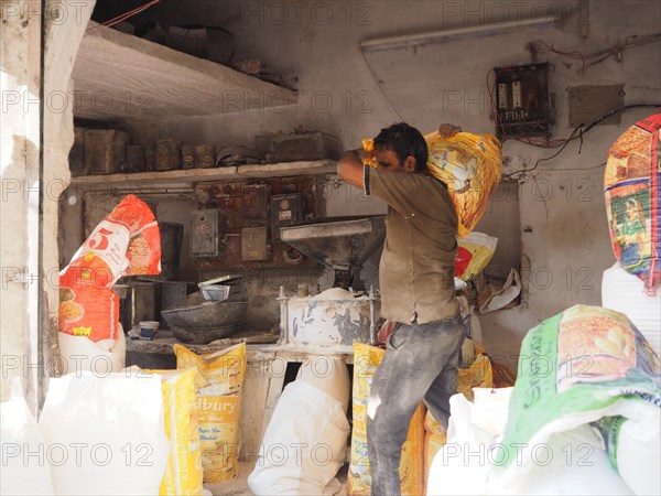 Vendor grinding fresh flour at market stall