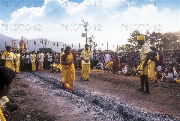 A woman carrying a child on her hip and running on burning coal