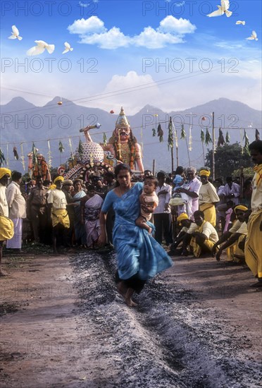 A woman carrying a child on her hip and running on burning coal