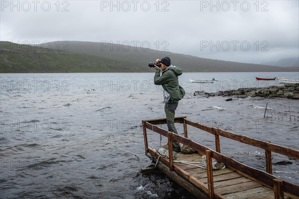 Hiker photographed on a wooden footbridge above Lake Leitisvatn