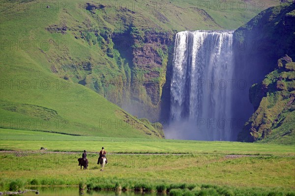 Women riders in front of waterfall