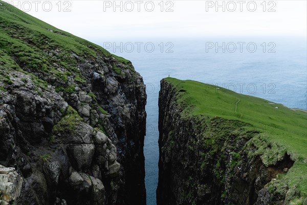 Small person standing on cliff with deep crevice