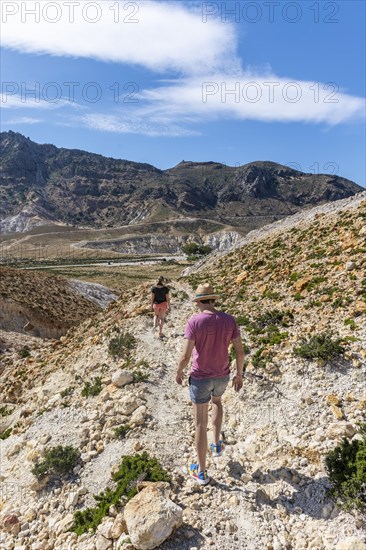 Three tourists hiking in a volcanic caldera with pumice fields